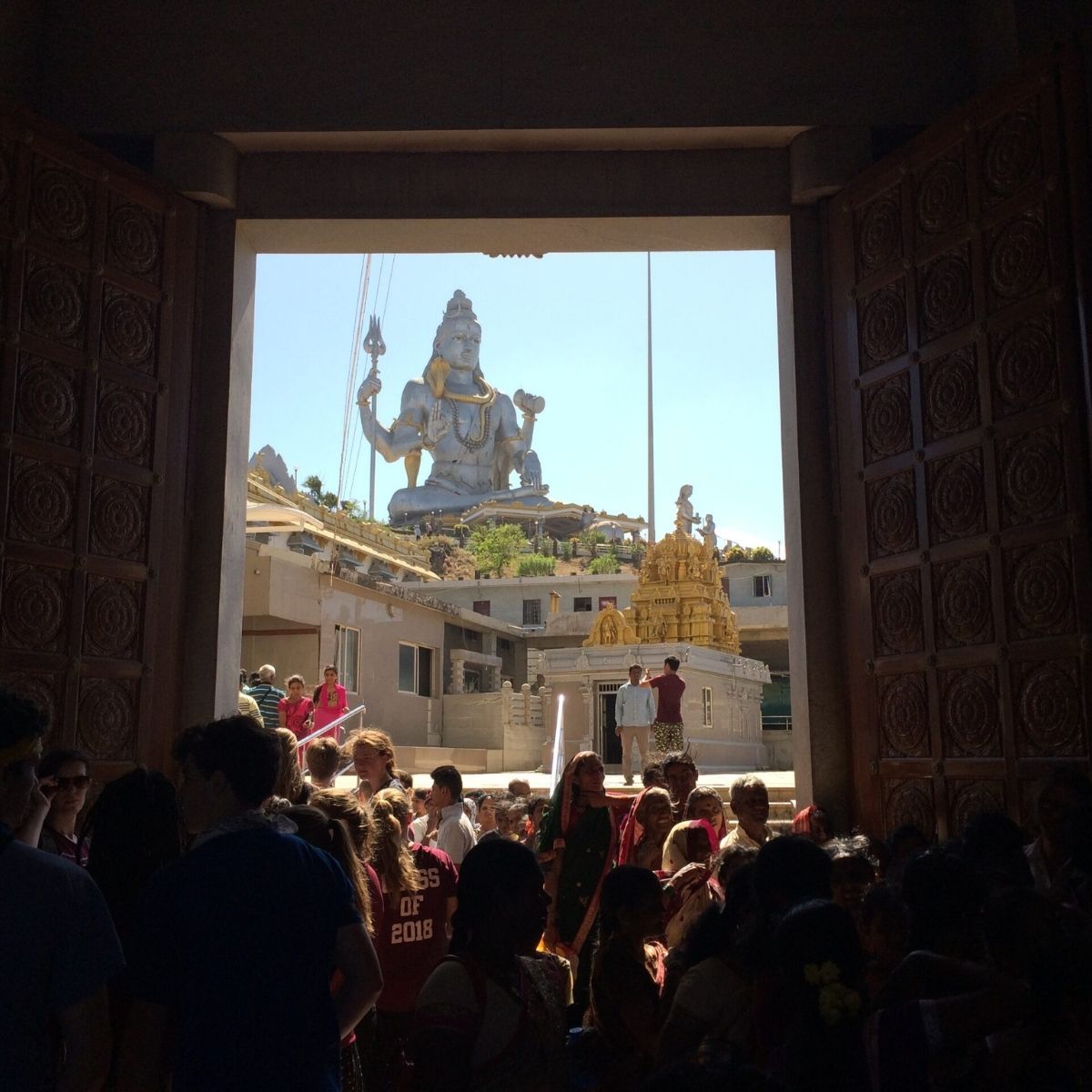 Visitantes entrando en un templo hindú con una gran estatua de Shiva