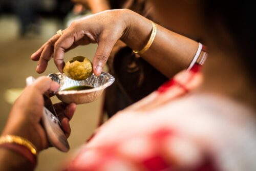 Authentic flavors of Mumbai Female traveler trying traditional pani puri during a street food tour through the streets of Mumbai.